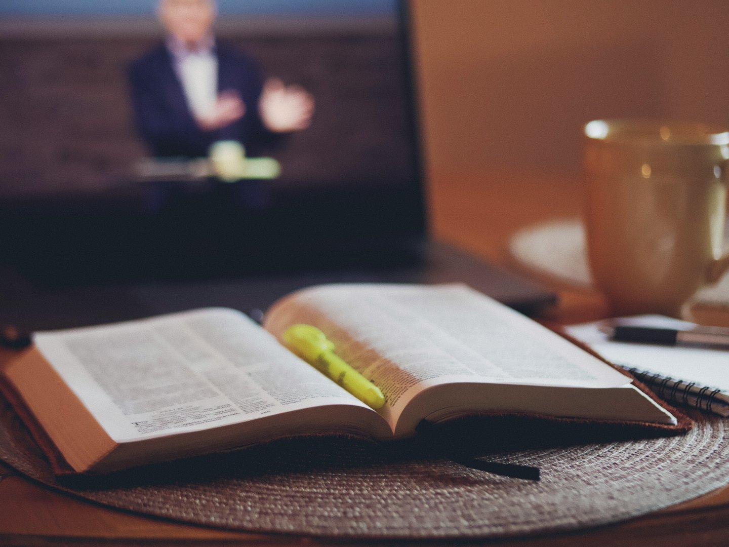 كتاب مفتوح ودفتر ملاحظات وقلم على طاولة خشبية.